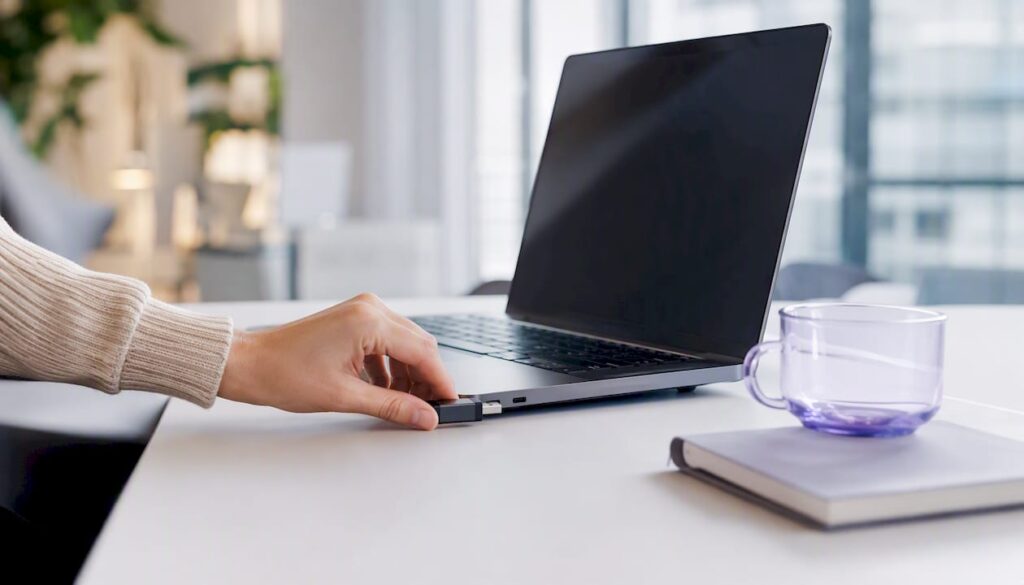 Eine Hand schließt ein SEO-Gerät an den Laptop an.