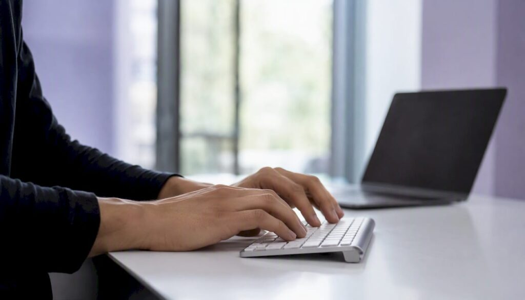 Entwickler tippt auf der Tastatur am Arbeitsplatz