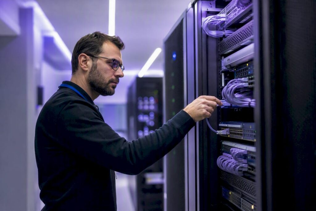 Hände, die ein Kabel am Server-Rack anschließen